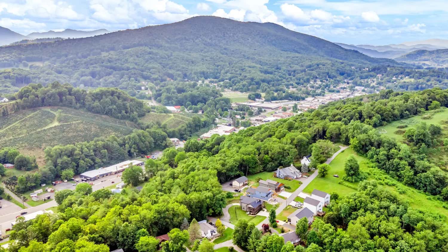 Aerial view of a small mountain town nestled in green Blue Ridge ridgelines near West Jefferson, NC